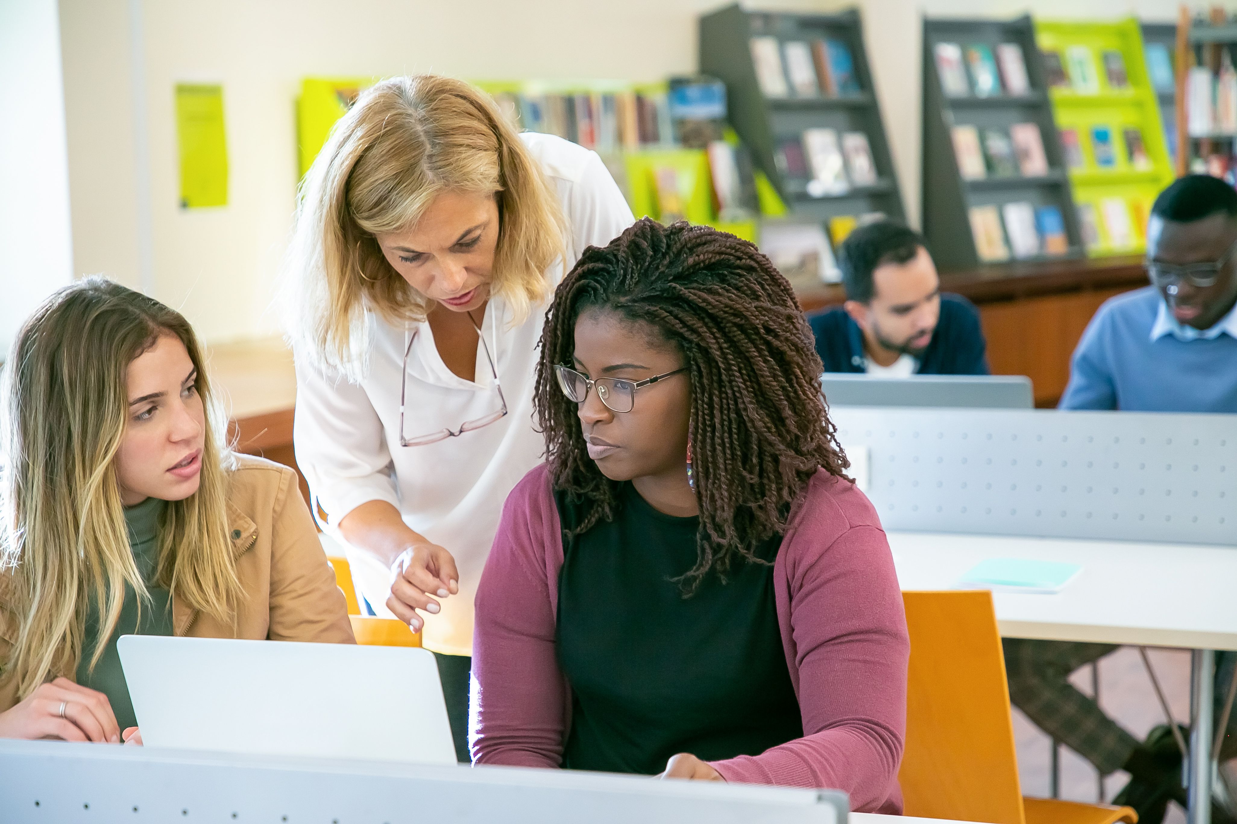 People In A Library On Laptops